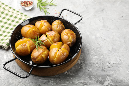 Tasty baked potatoes with rosemary served on light grey table, space for textの写真素材