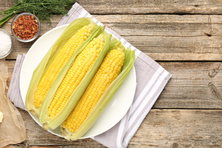 Tasty boiled corncobs, dill and spices on wooden table, flat lay. Space for text