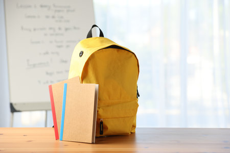 Backpack and notebooks on desk in classroomの写真素材