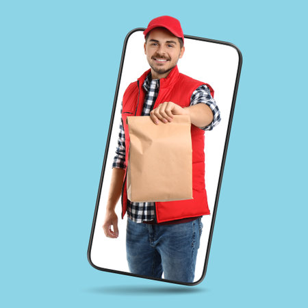 Food delivery service worker giving paper bag out of mobile phone display against light blue background. Online orderの写真素材