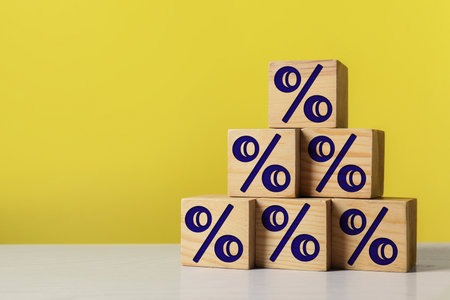 Percent signs on wooden cubes against yellow background. Space for textの写真素材