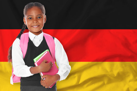 Little girl with backpack and notebooks against flag of Germanyの写真素材