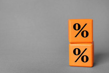 Percent signs on orange cubes against grey background. Space for textの写真素材