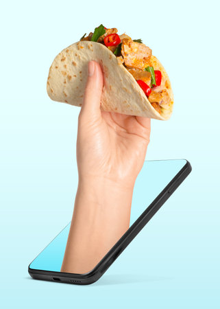 Food ordering and delivery service. Woman's hand with tasty taco, sticking out of mobile phone display against light blue background, closeupの写真素材