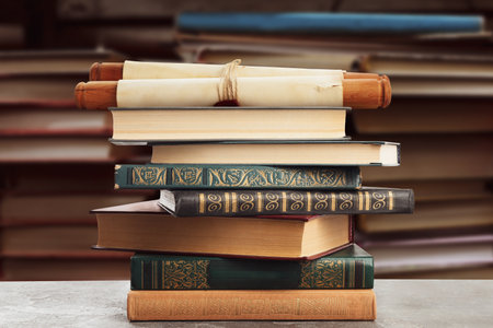 Old rolled paper scroll and books on table in libraryの写真素材