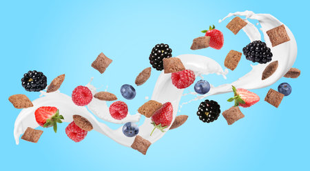 Splashing milk with sweet corn pads and fresh berries in air against light blue background. Healthy breakfastの写真素材