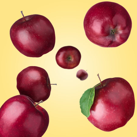 Fresh red apples swirling in air against pale orange background