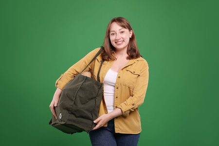 Recycling. Smiling woman with bag full of different waste paper on green background