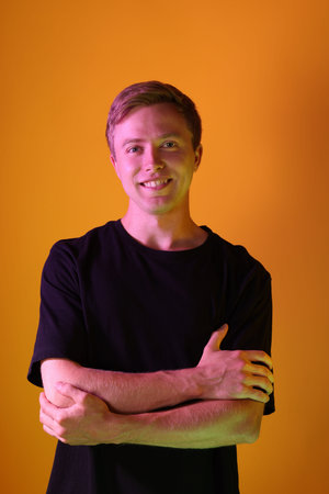 Portrait of smiling man in neon lights against orange background