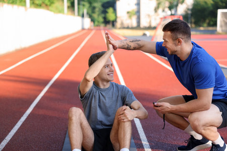 Young man with professional personal trainer giving high five outdoorsの写真素材