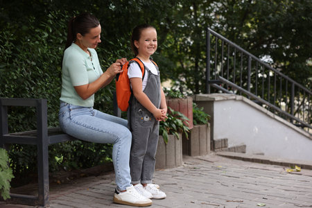 Mother taking her daughter to school outdoors