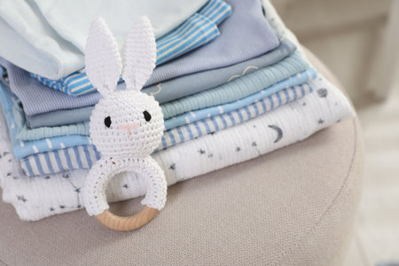 Stack of clean baby clothes and toys on pouf indoors, closeupの写真素材