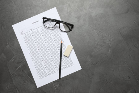 Student passing exam. Answer sheet, glasses, pencil and eraser on gray textured table, flat lay....