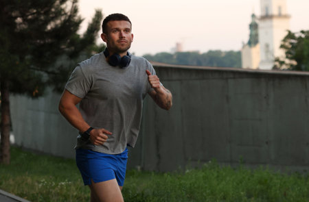 Athletic young man in sportswear running outdoors, space for text