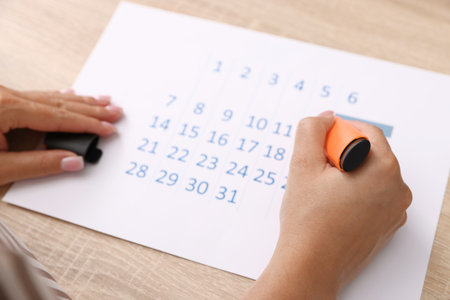 Business planning. Woman using calendar at wooden table in office, closeupの写真素材