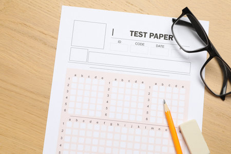 Answer sheet, eraser, pencil and glasses on wooden table, flat lay. Student passing examの写真素材