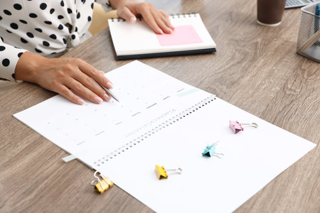 Woman using business planner at wooden table in office, closeupの写真素材