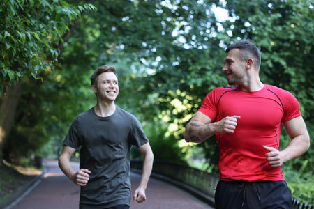 Young man running with professional personal trainer outdoors