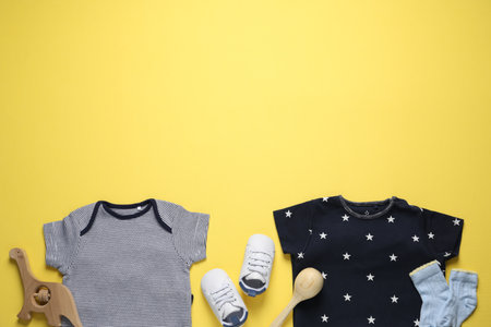Stylish baby clothes and accessories on yellow background, flat lay. Space for textの写真素材