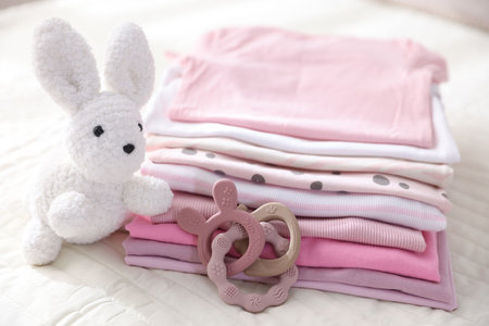 Stack of clean baby clothes and accessories on bed lines, closeupの写真素材