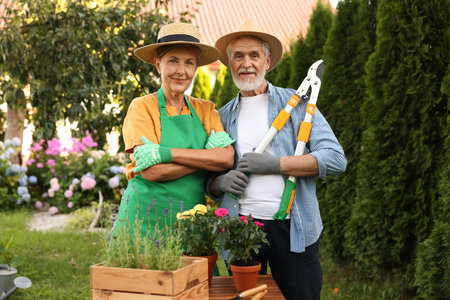 Happy senior couple in gloves and hats in gardenの写真素材