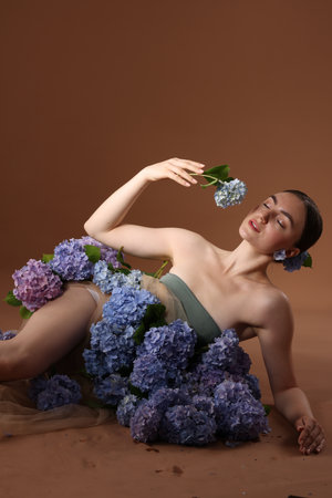 Beautiful young woman with hortensia flowers on brown backgroundの写真素材