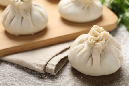 Uncooked khinkalis (dumplings) and cilantro on wooden table, closeupの写真素材