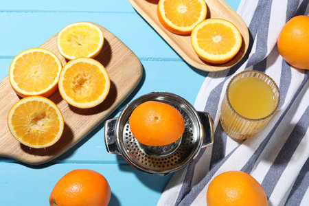 Freshly squeezed orange juice, fruits and juicer on blue wooden table, flat lay