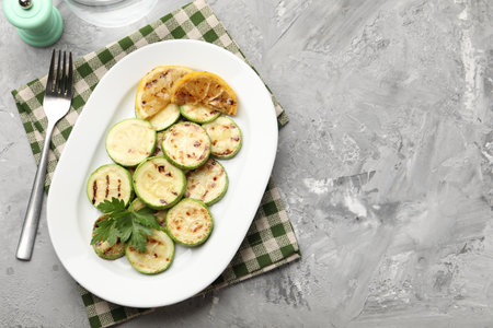 Delicious fried courgette slices with lemon and parsley served on gray table, flat lay. Space for textの写真素材