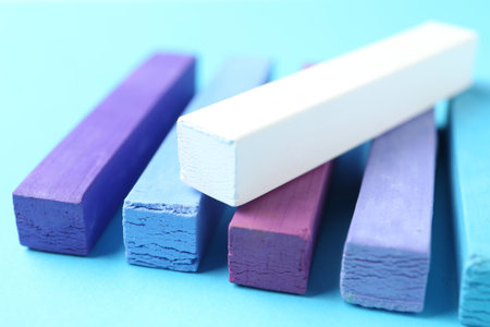 Colorful chalk pastels on light blue background, closeup