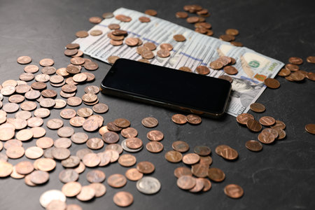 Smartphone, dollars and coins on black table, closeupの写真素材