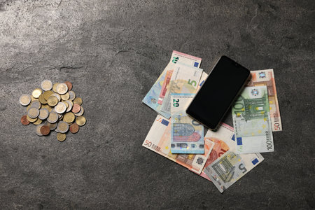 Smartphone, euro banknotes and coins on grey table, flat layの写真素材