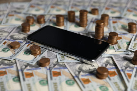 Smartphone, dollar banknotes and coins as background, closeupの写真素材