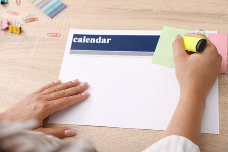 Business planning. Woman using calendar at wooden table in office, closeupの写真素材