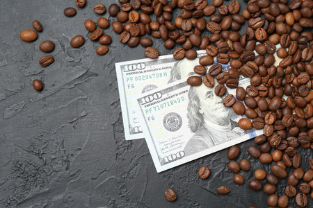 Dollar banknotes and roasted coffee beans on dark textured table, flat layの写真素材
