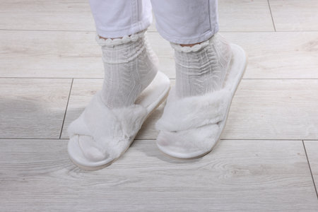 Woman in fluffy white slippers on light wooden floor, closeupの写真素材
