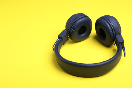 Pair of stylish blue headphones on yellow background. Space for textの写真素材