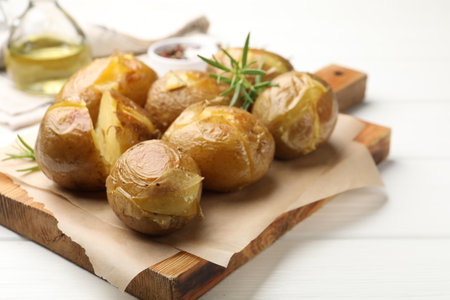 Tasty baked potatoes with rosemary served on white wooden table, closeupの写真素材