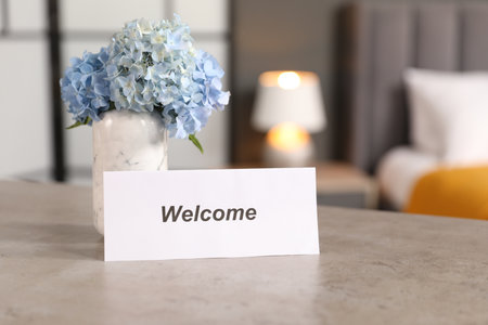 Card with word Welcome and hydrangea flowers on grey table indoorsの写真素材