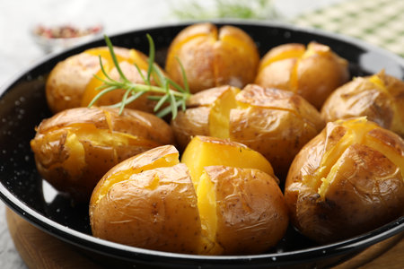 Tasty baked potatoes with rosemary served on table, closeupの写真素材