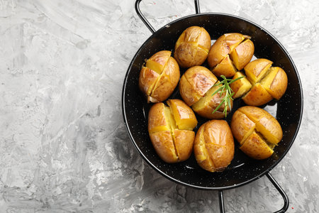 Tasty baked potatoes with rosemary served on light grey table, top view. Space for textの写真素材