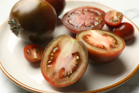 Whole and cut brown tomatoes on white marble table, closeupの写真素材