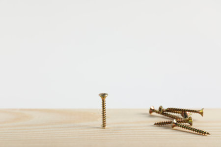 Metal screws and wooden plank on white background, closeup. Space for textの写真素材