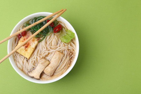 Tasty ramen with enoki and king oyster (eryngii) mushrooms on green background, top view. Space for textの写真素材