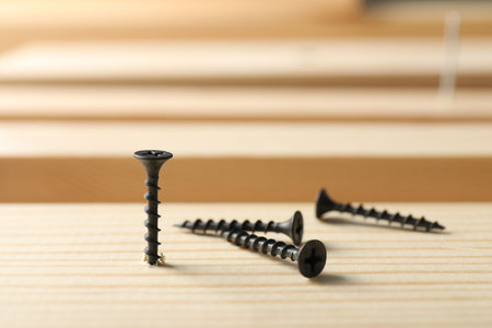 Metal screws and wooden plank on table, closeupの写真素材