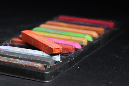 Set of colorful chalk pastels on black background, closeup