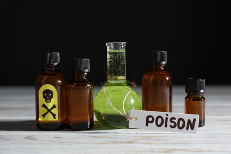 Bottles with poisons on wooden table against black backgroundの写真素材