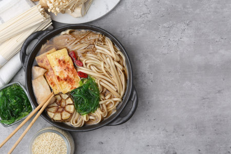 Tasty ramen with enoki and king oyster (eryngii) mushrooms on light grey table, flat lay. Space for...