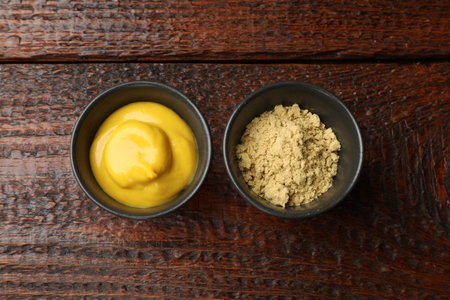 Different types of mustard on wooden table, flat lay