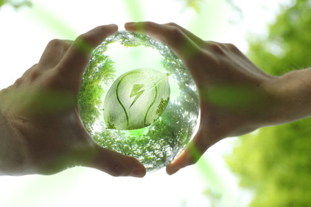 Electricity and nature. Man holding crystal ball with light bulb and lightning symbol inside outdoors, closeupの写真素材
